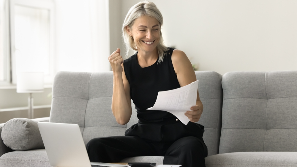 Happy successful mature investor woman in black celebrating profit