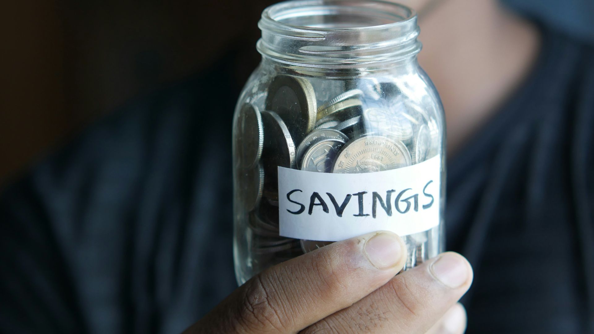 a man holding a jar with a savings label on it