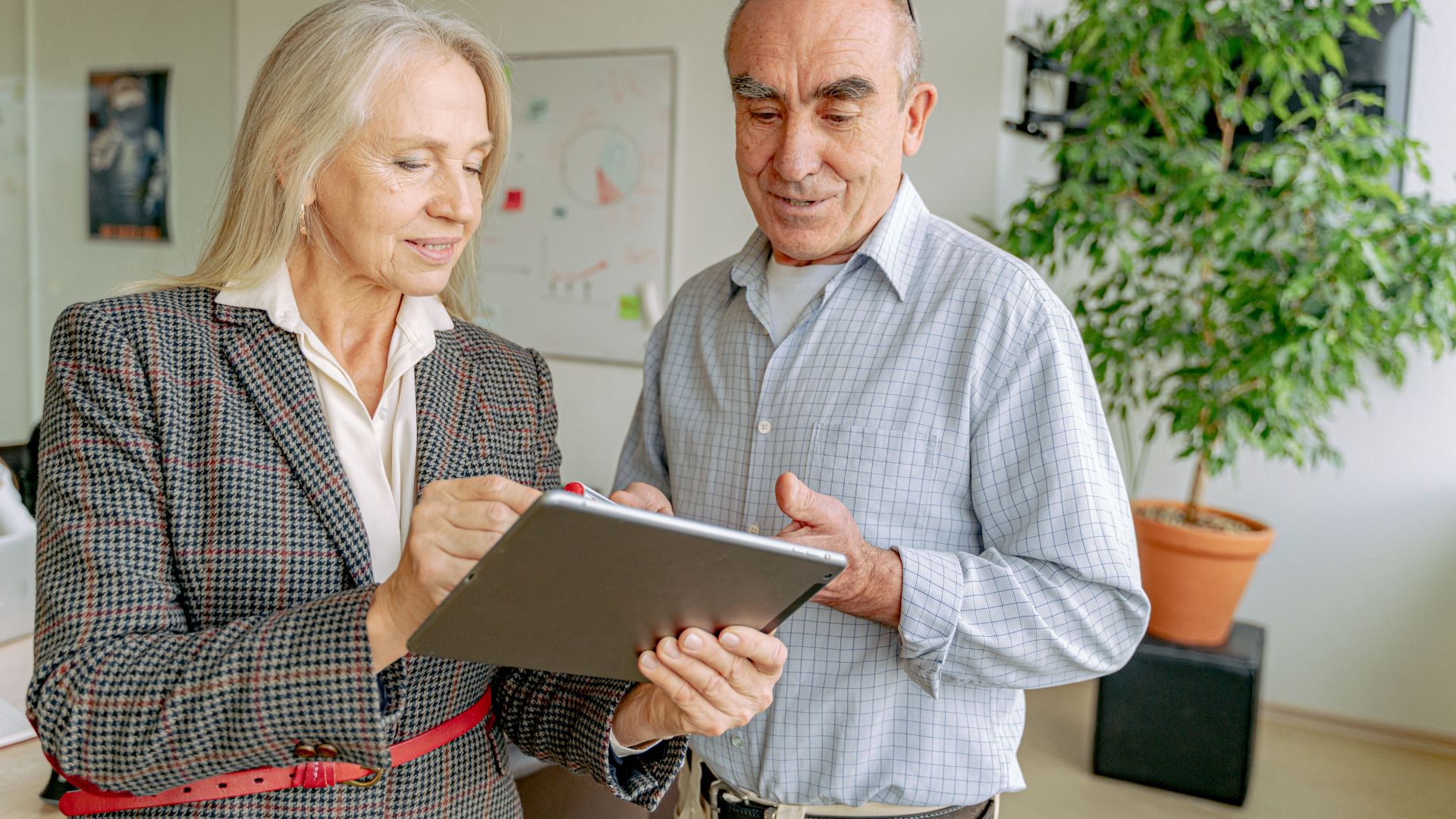 Senior professionals collaborating on a project using a digital tablet in a modern office setting.