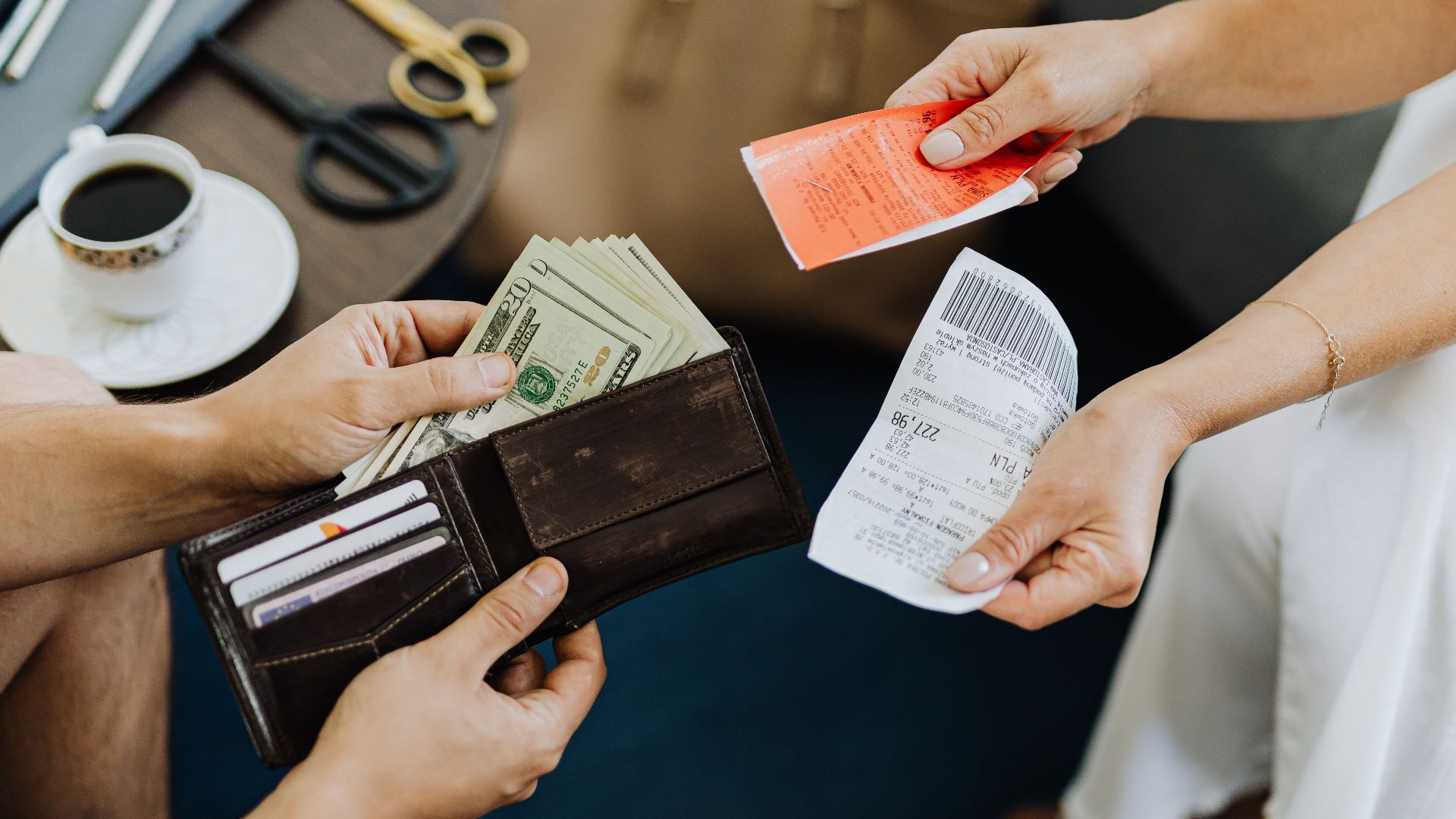 Close-up of a financial transaction involving cash and receipts over a coffee table.