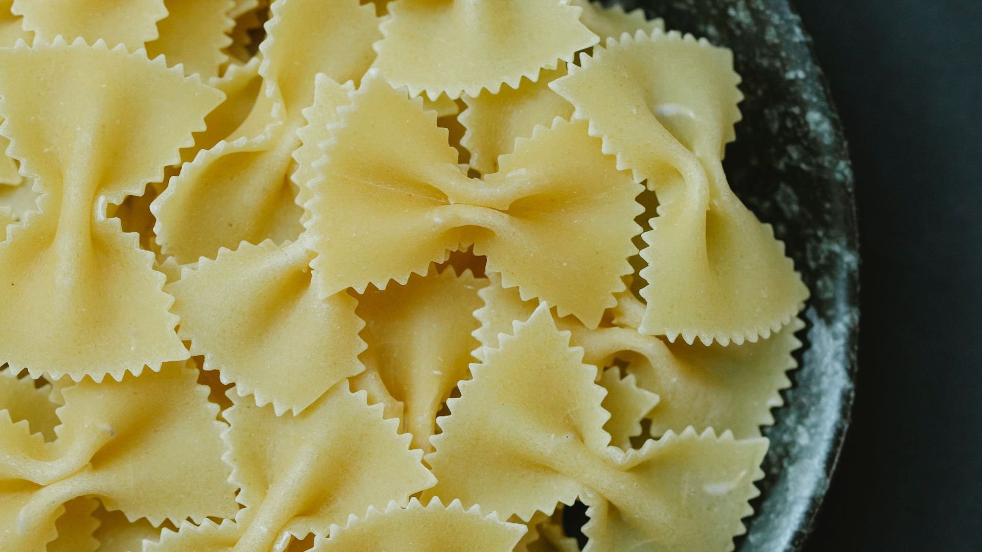 From above of traditional Italian raw dried farfalle pasta in bowl on table