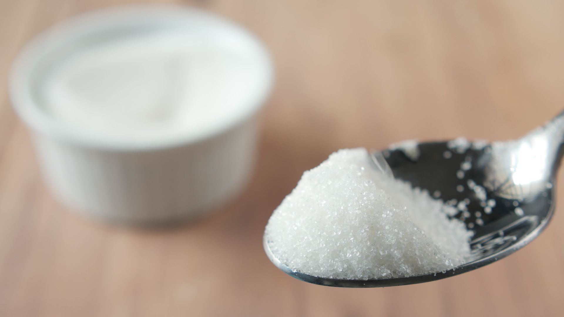 A close-up shot of granulated sugar on a spoon, highlighting texture and shine.