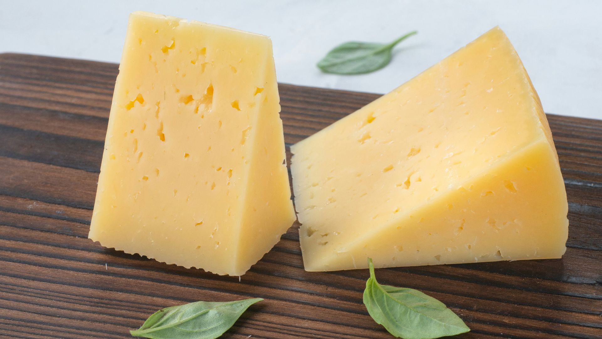 a couple of pieces of cheese sitting on top of a wooden cutting board