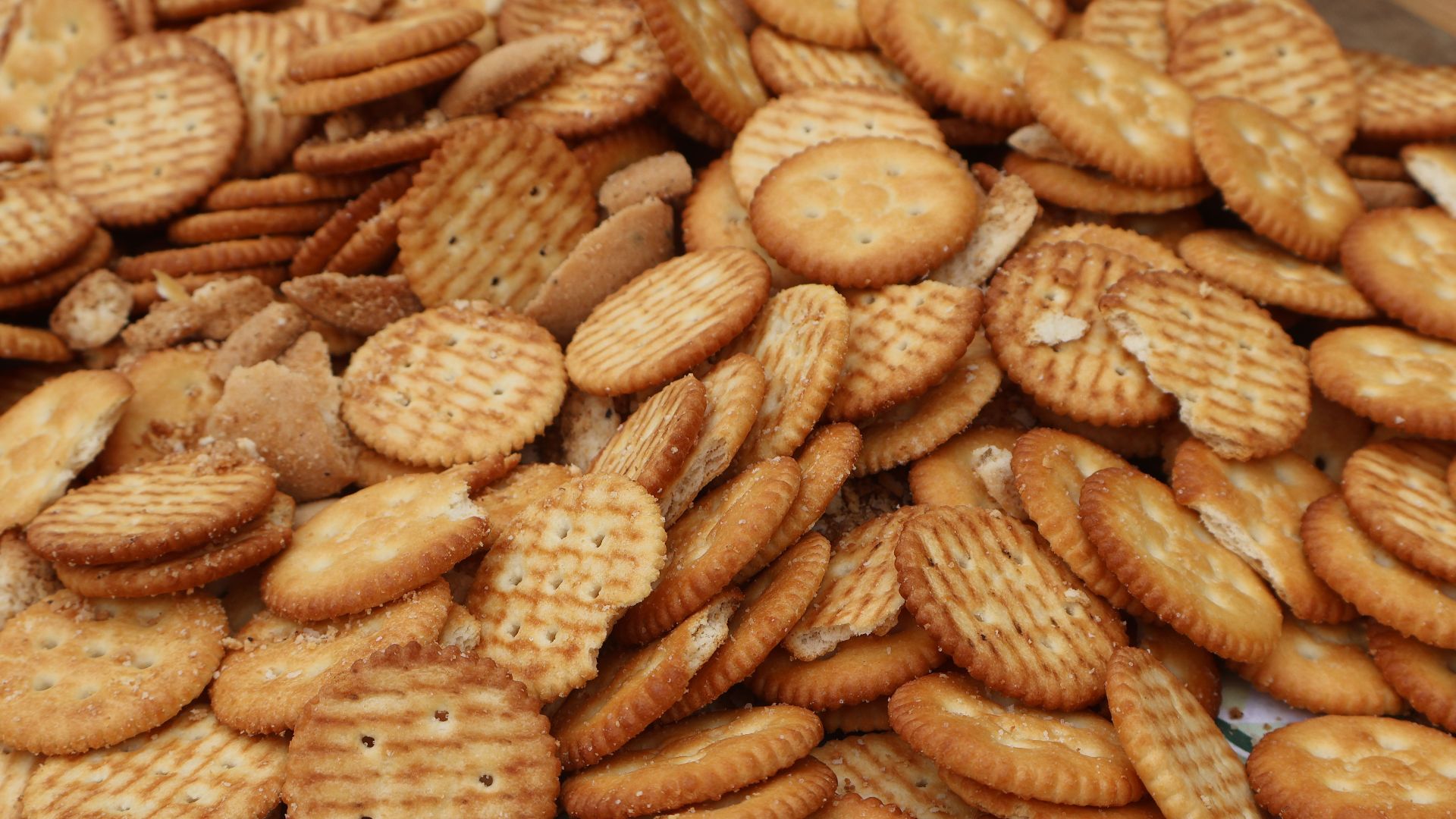 A collection of assorted round crackers stacked in a pile, perfect for snacking or party platters.