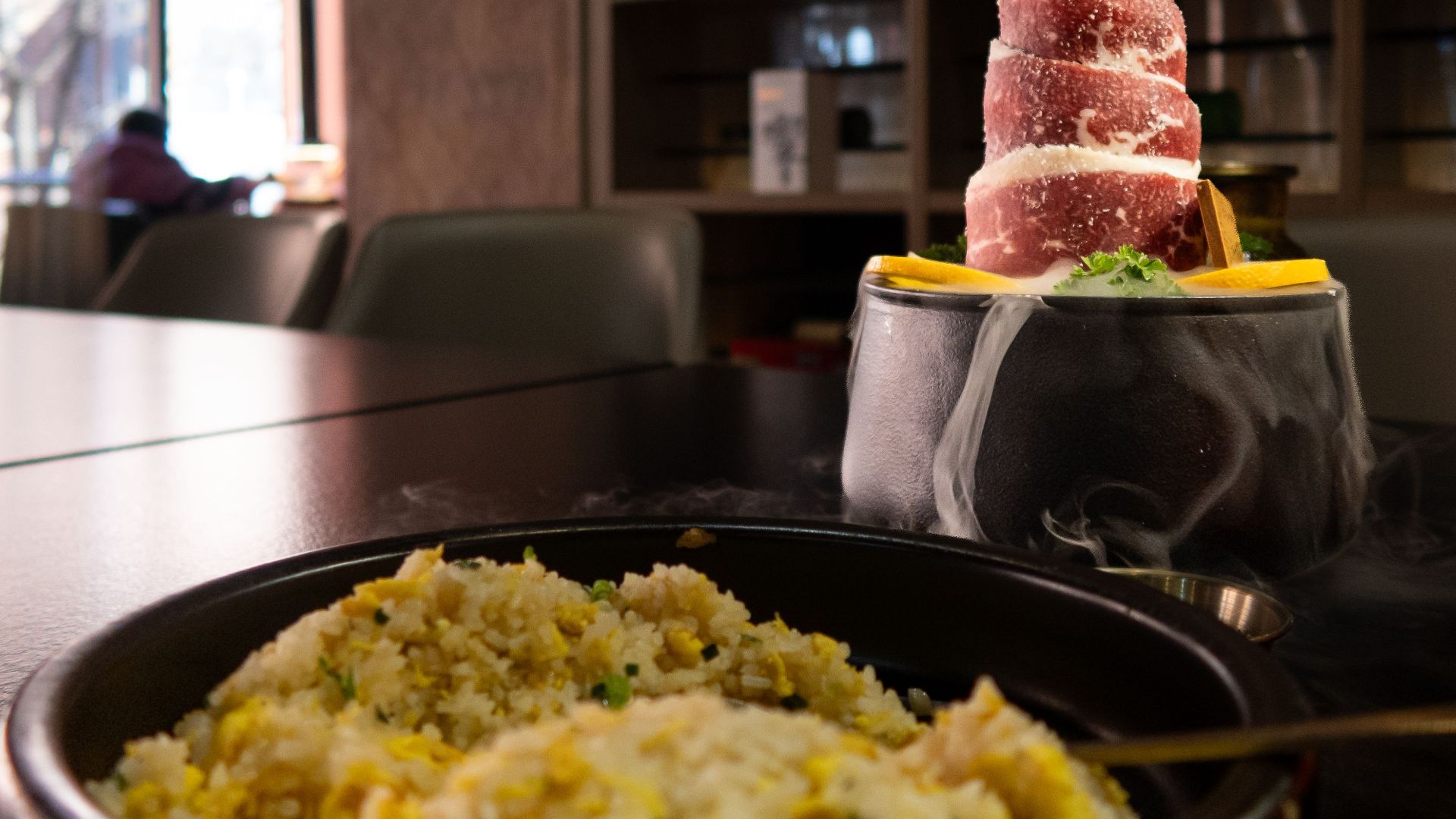 A visually striking dish featuring a frozen meat tower and fried rice set in a cozy restaurant setting.