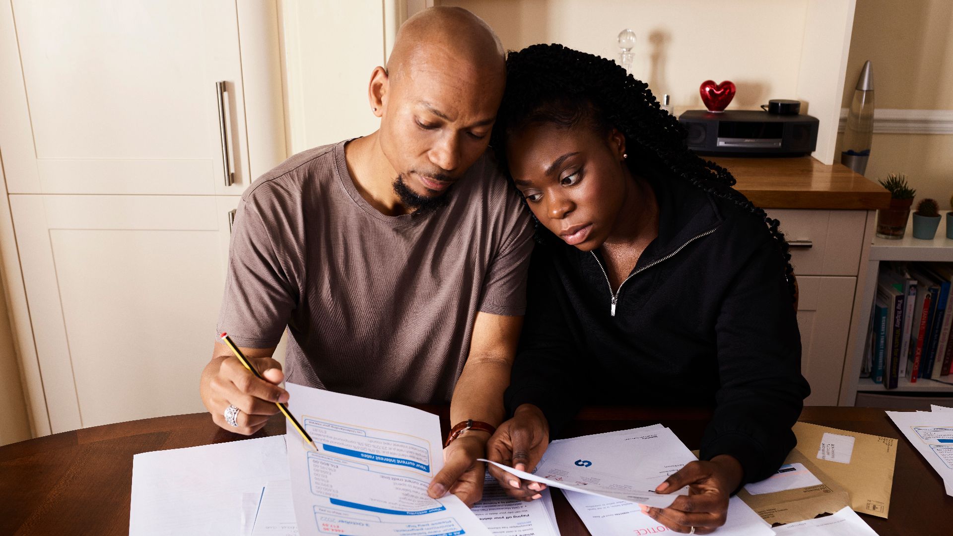 A couple sitting at a table reviewing financial documents, highlighting domestic budgeting.
