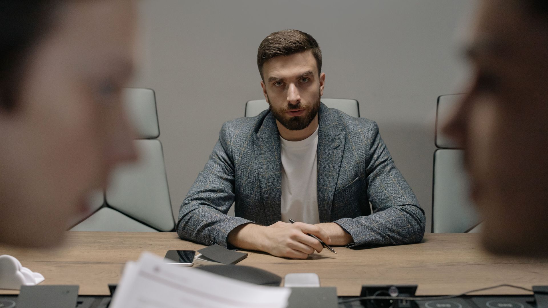 Serious businessmen engaged in a formal meeting around a conference table.