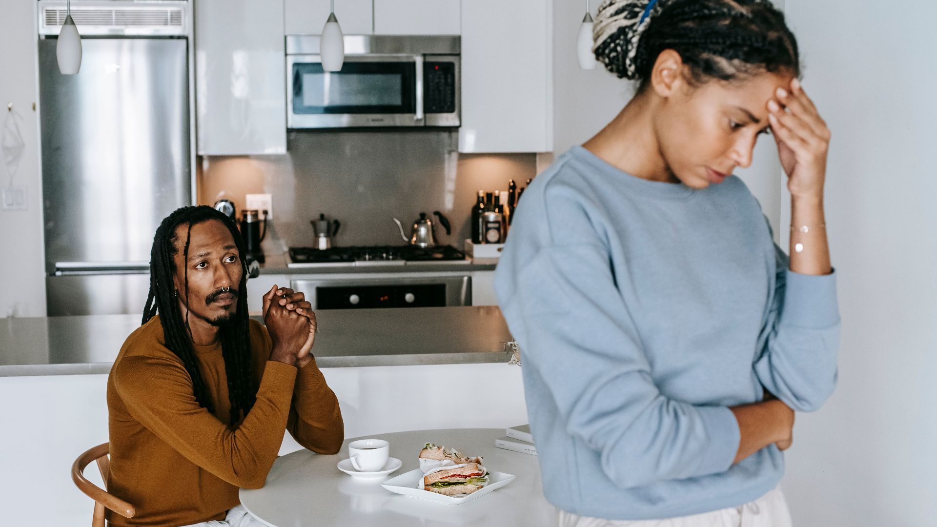 Young African American man sitting at table and arguing with woman while having breakfast at home