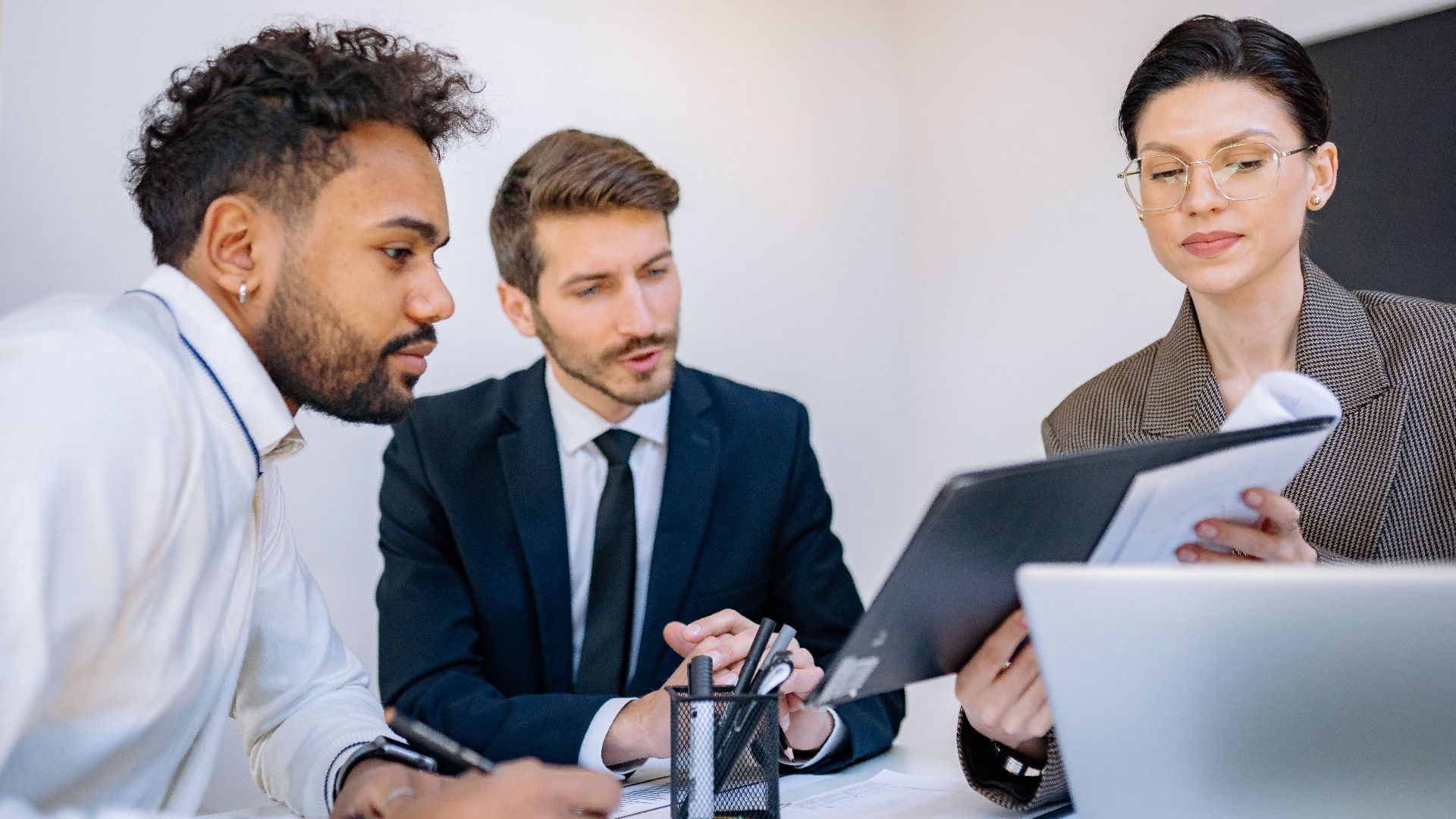 Three business professionals engaged in a focused office meeting, discussing documents.