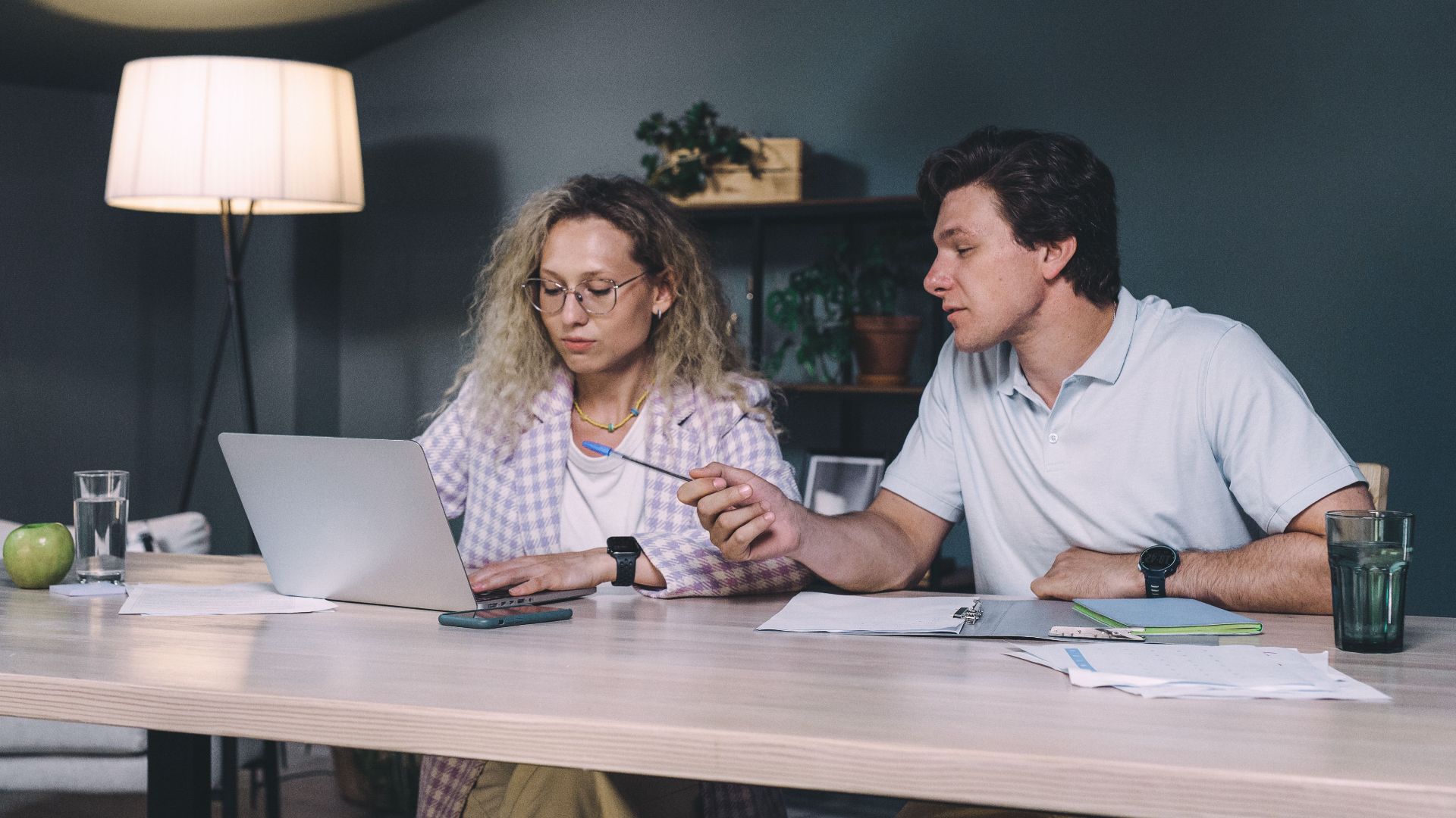 Two professionals working together at a laptop in a contemporary office setting, focusing on teamwork.