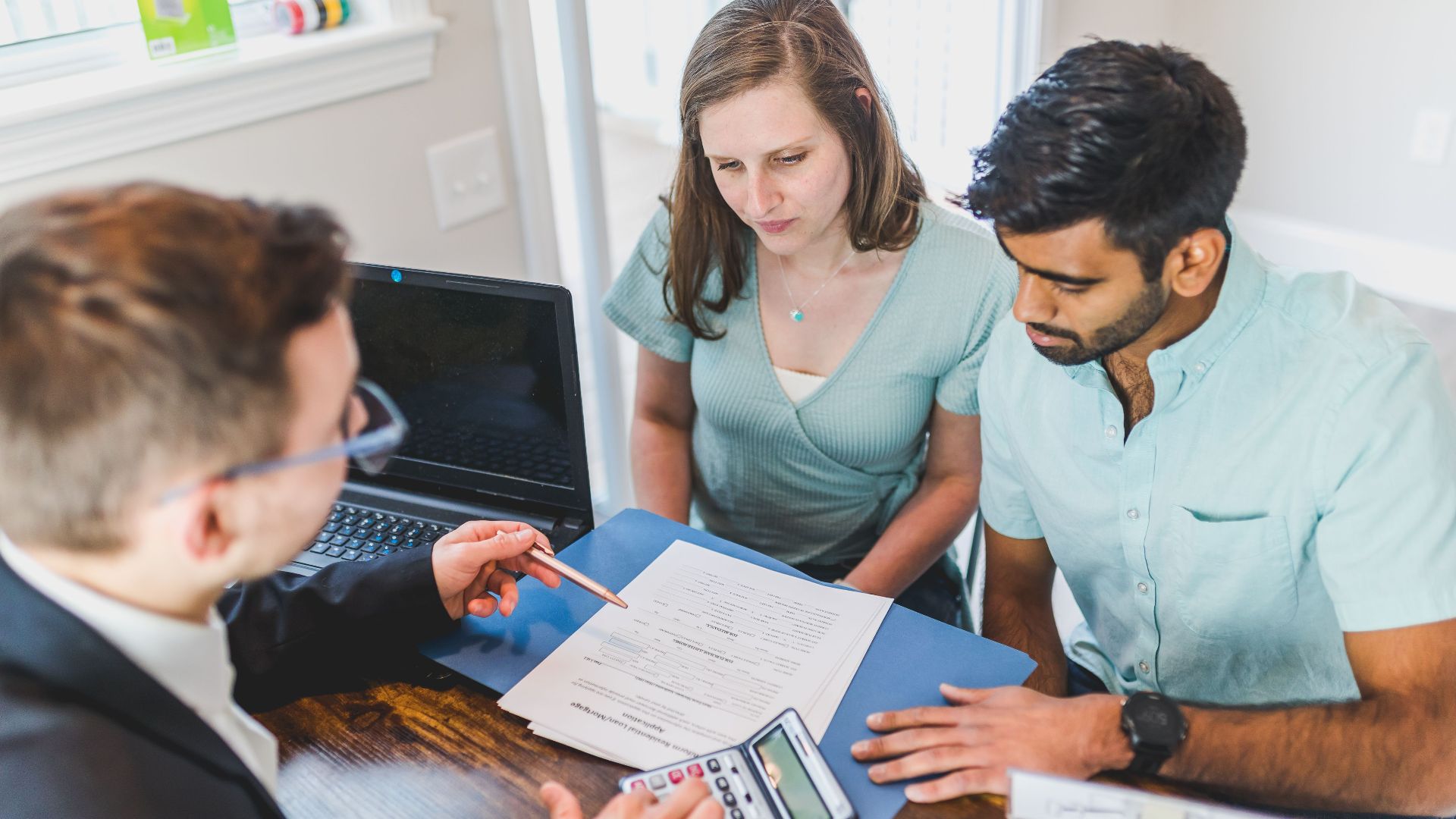 Young couple meeting with real estate agent to discuss property purchase.