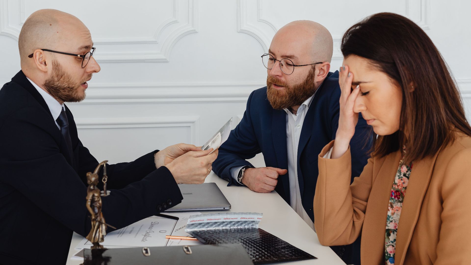 Lawyer discussing divorce settlement with distressed couple during tense meeting.