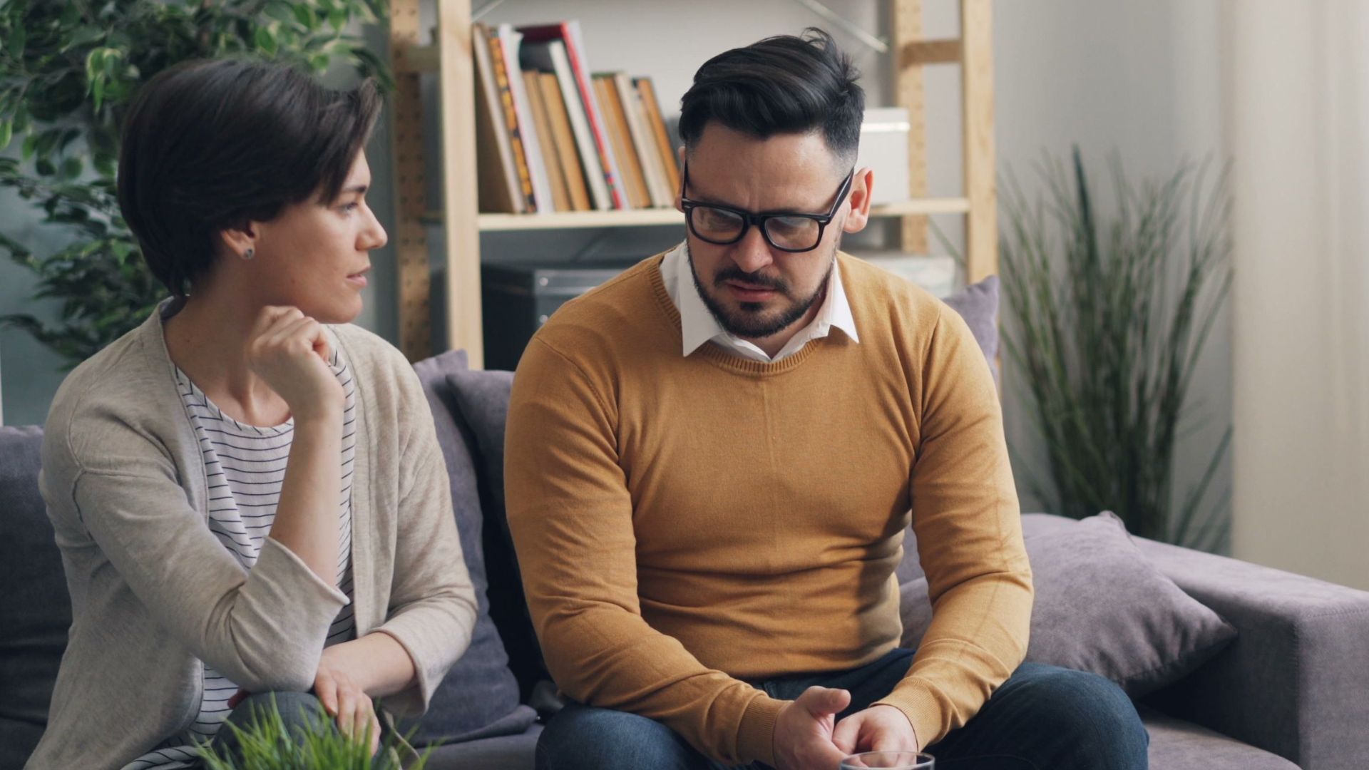 A couple engaged in a counseling session with a therapist in a cozy room.