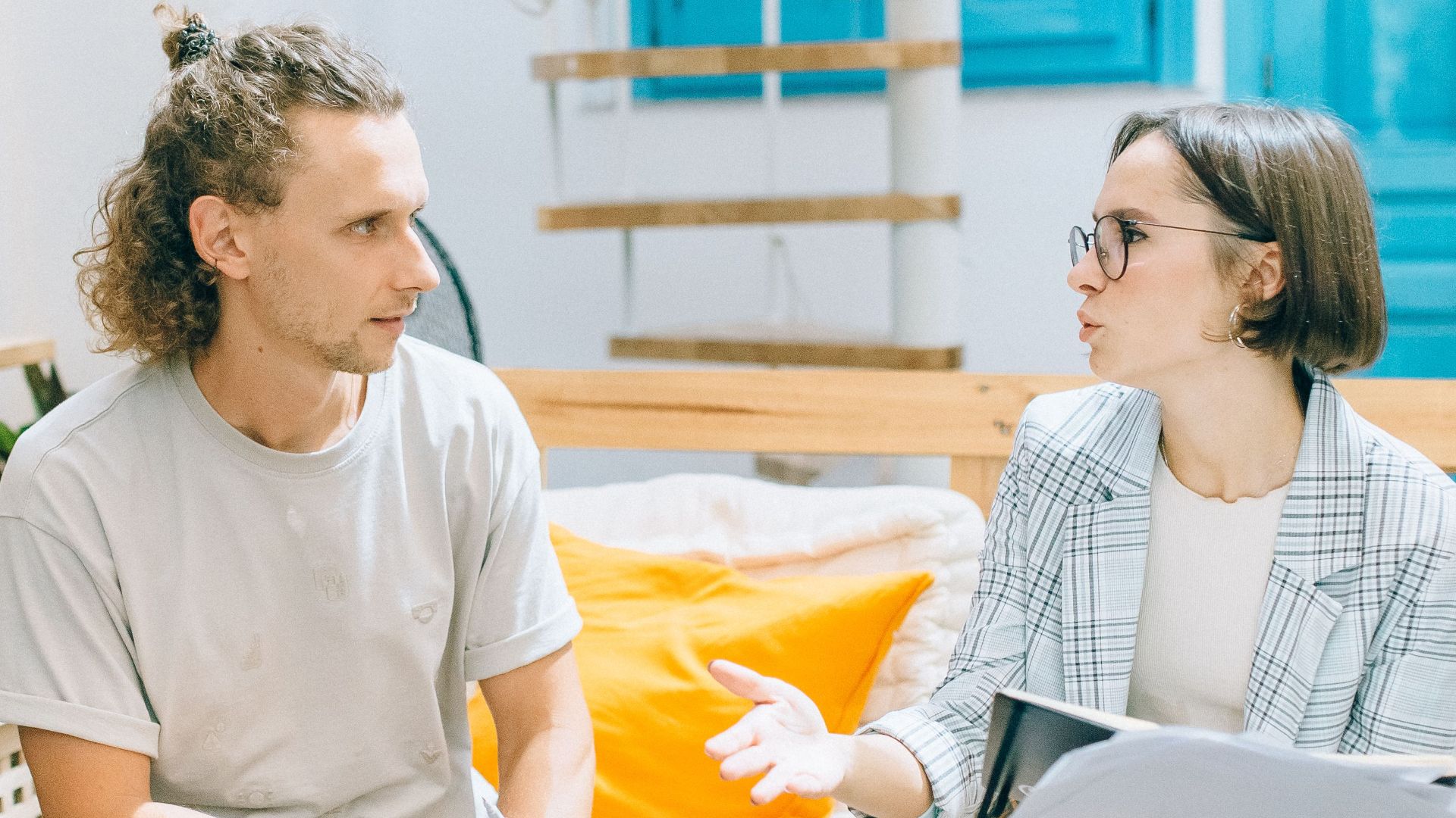A man and woman discussing work in a stylish, bright living room setting.