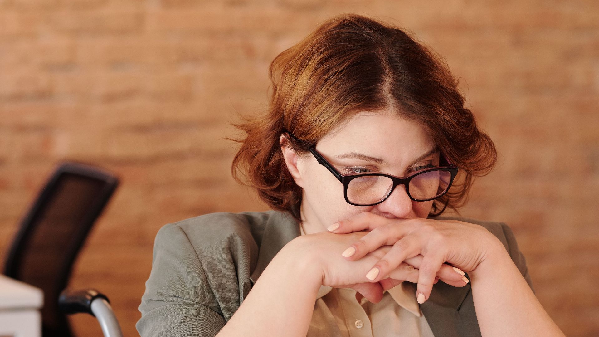 Female professional in wheelchair, deep in thought at home office desk.