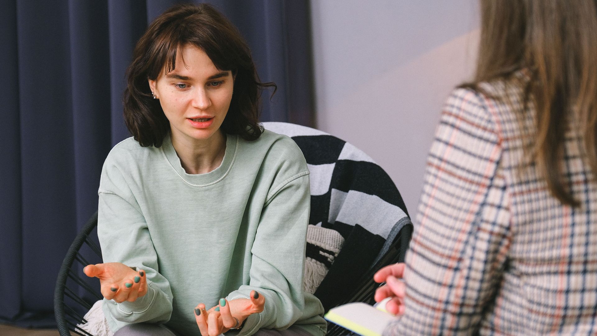 Calm female sitting on armchair and giving interview to concentrated woman in light room