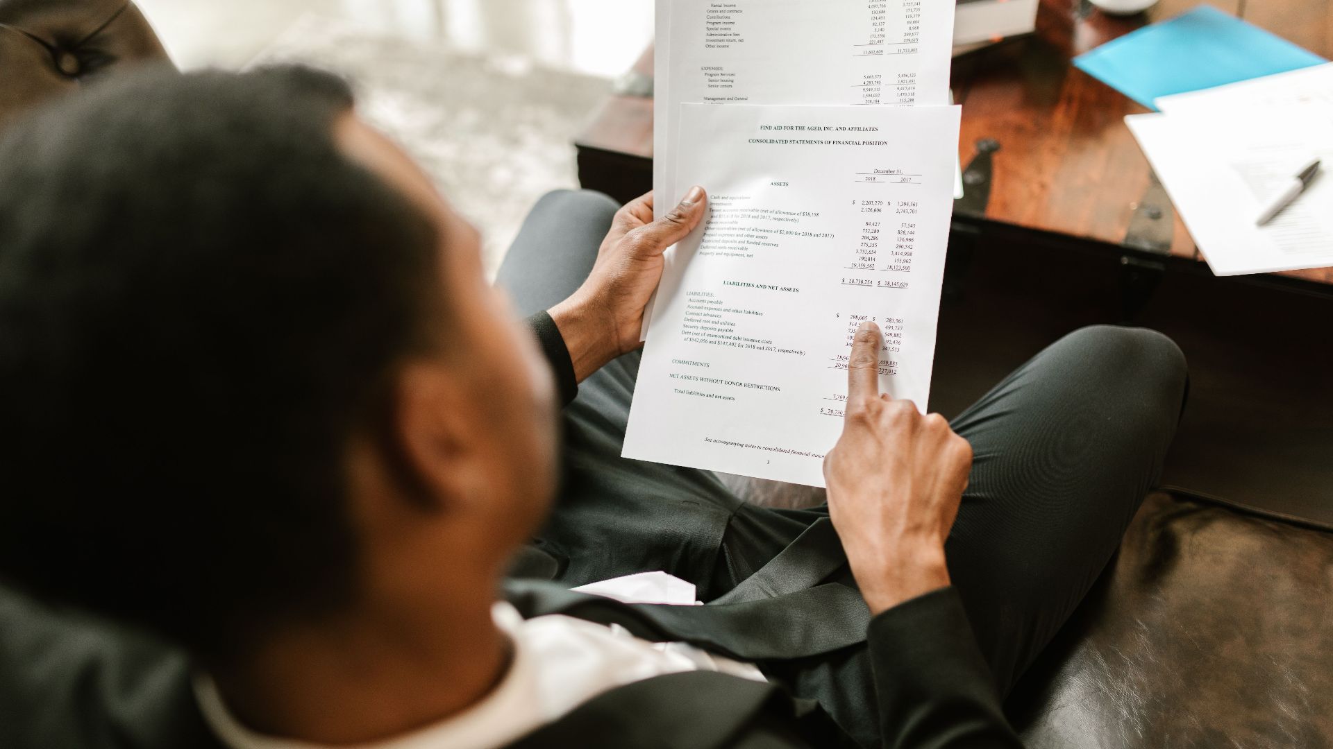 Business professional examining financial documents, focusing on analytics and paperwork in an office setting.