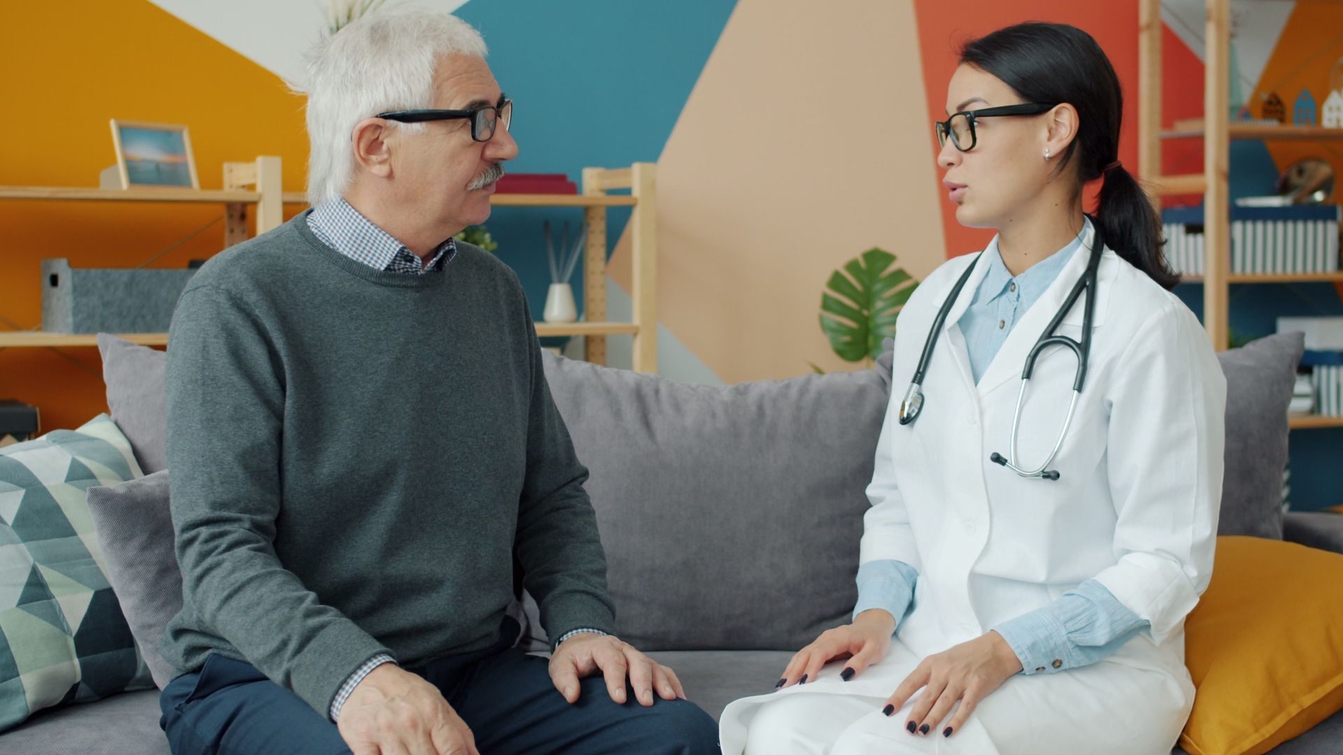Senior man consulting with female doctor in a colorful office setting.