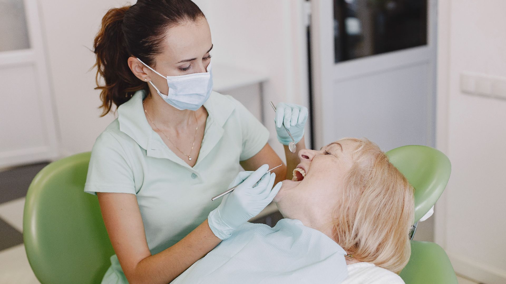 A female dentist examines a patient in a dental office, highlighting professional dental care.