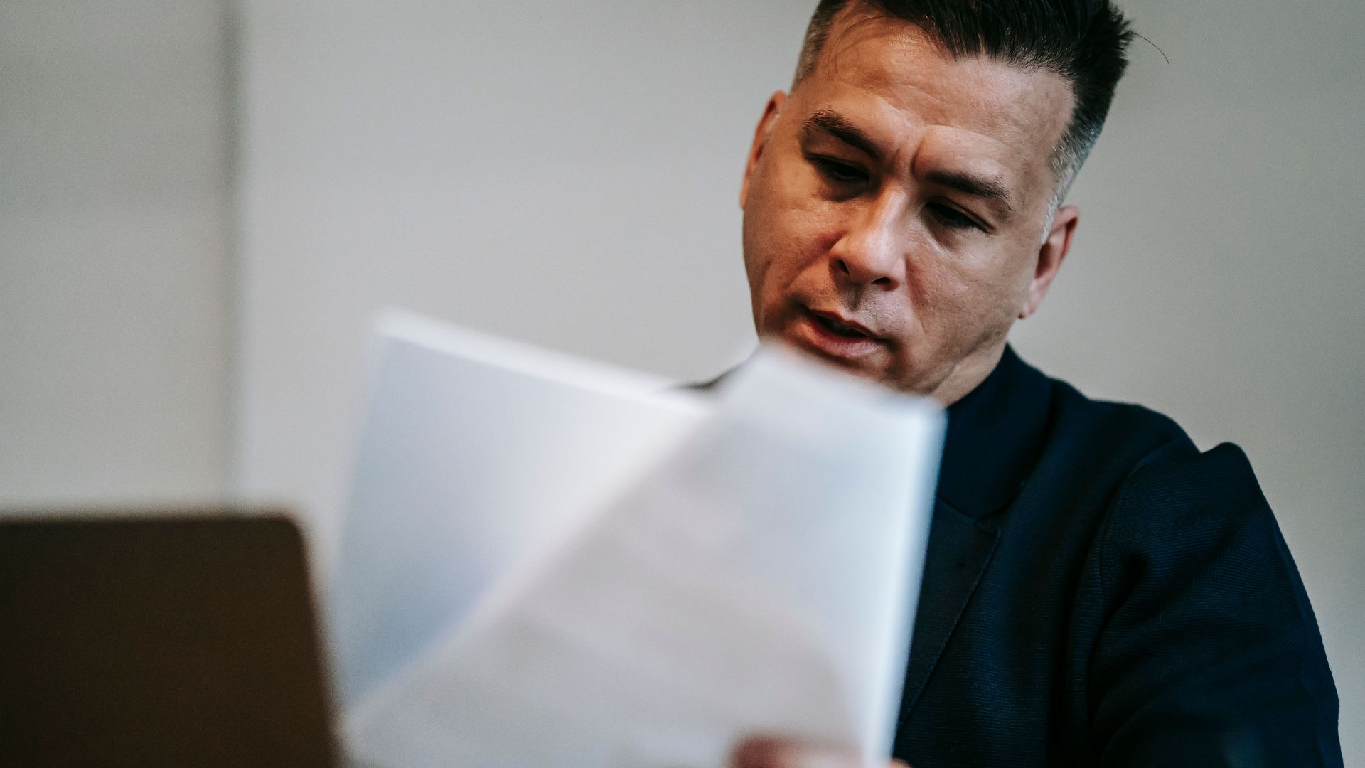 Professional man intently reviewing paperwork at his workstation indoors.