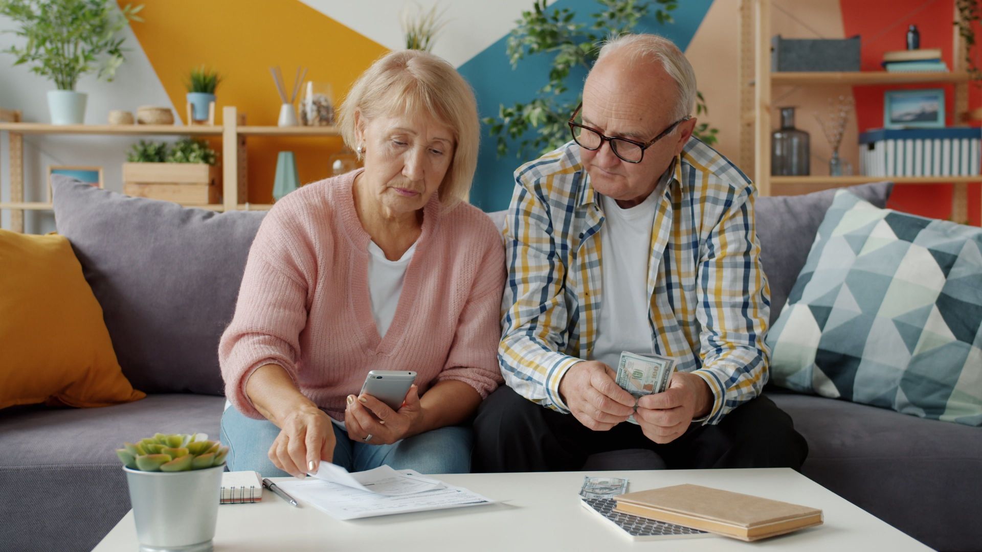 Senior couple managing household finances in cozy living room setting.