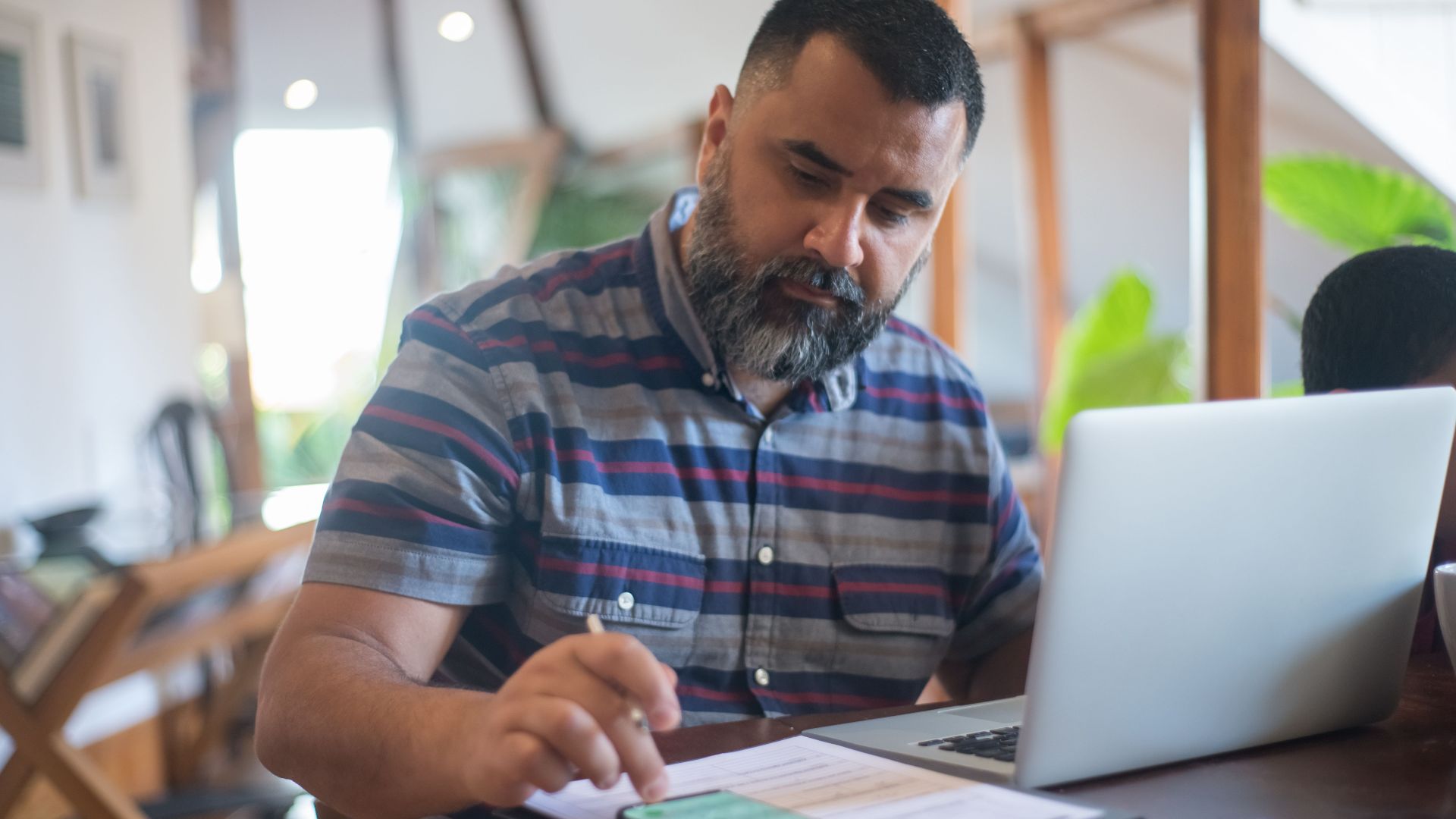 Professional man working at home office in Portugal using laptop and phone.