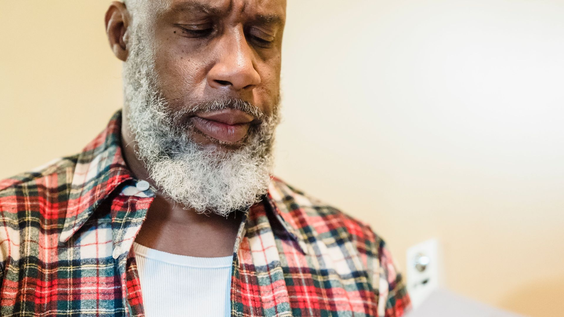 A mature man with a beard attentively reading documents indoors in a focused manner.