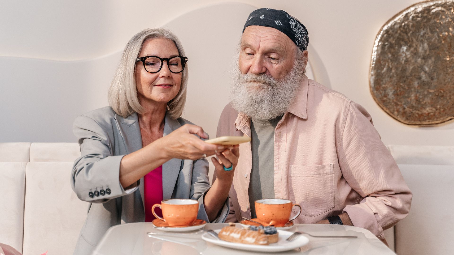 A happy senior couple shares coffee and pastries at a cozy café.