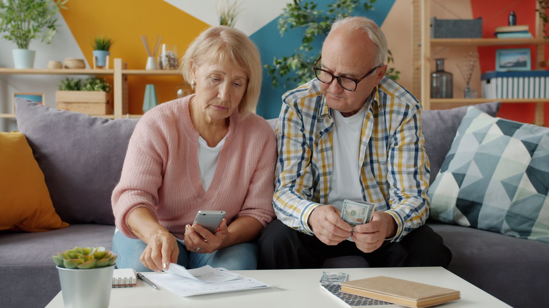 Senior couple managing household finances in cozy living room setting.