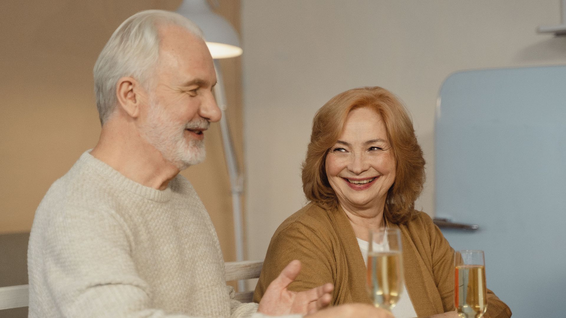 Elderly couple enjoying a joyful family dinner with champagne and fruit.