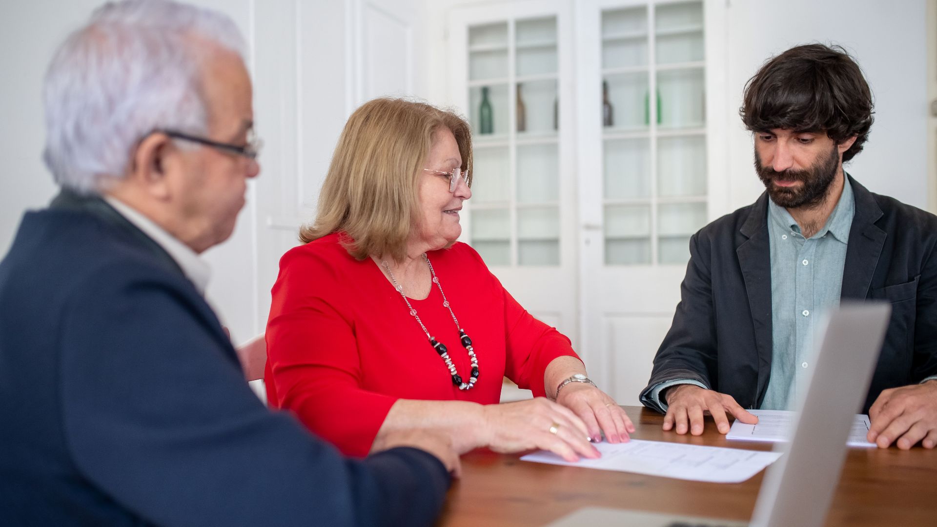 Three business professionals in a meeting, discussing documents and planning strategies indoors.