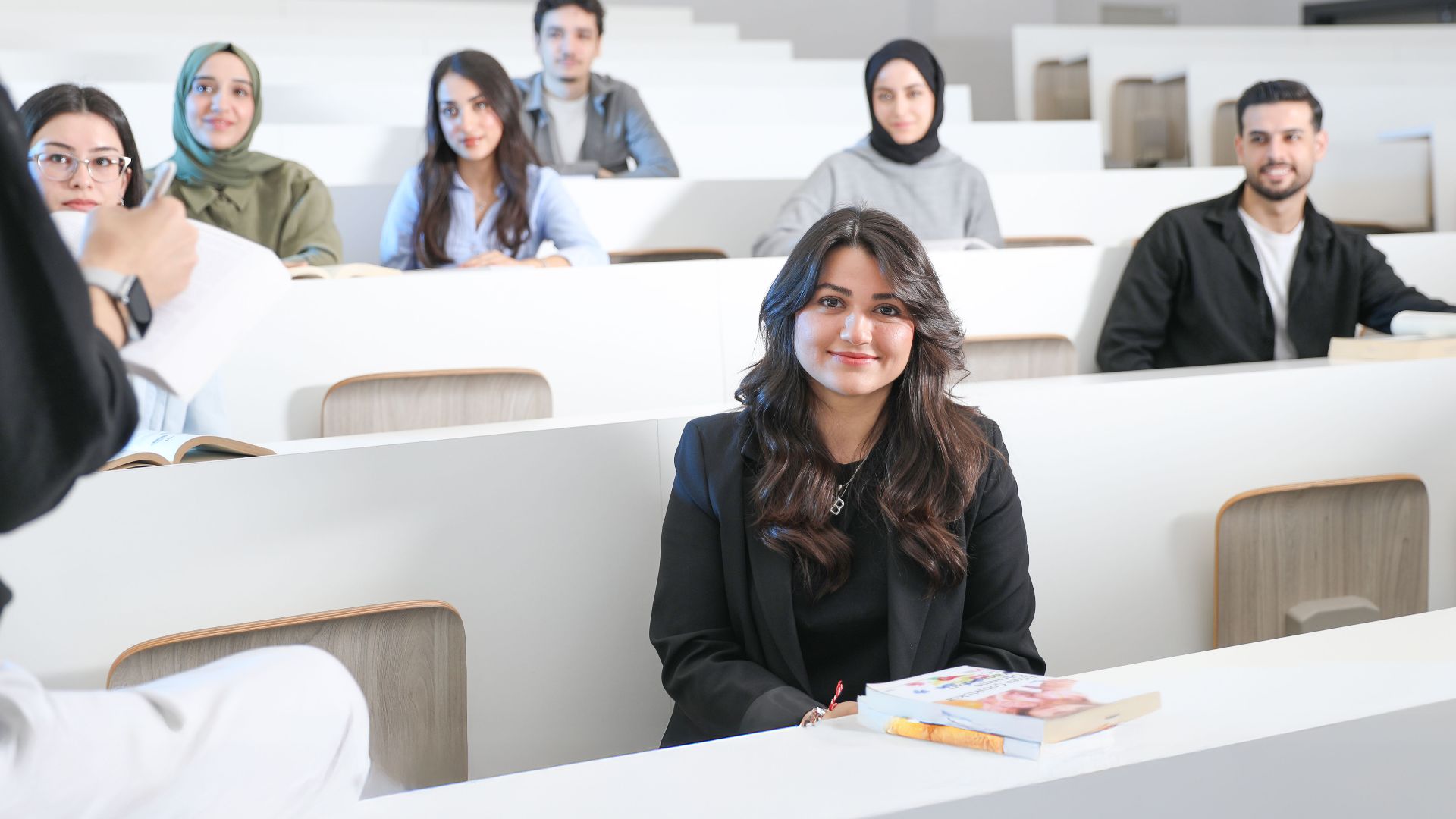 Students listening attentively in a bright university lecture hall.