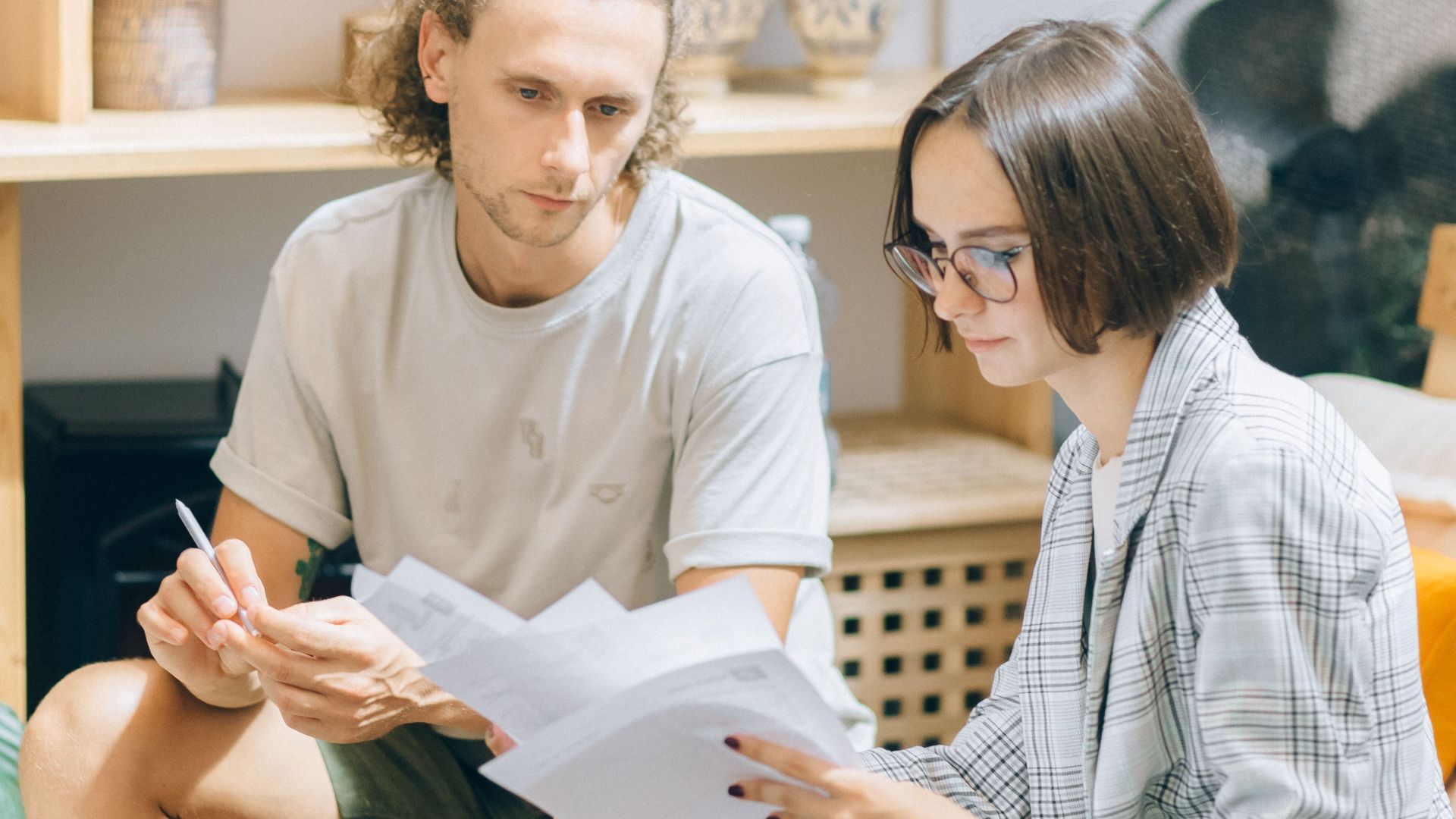 A man and woman discussing documents in a cozy workspace setting.