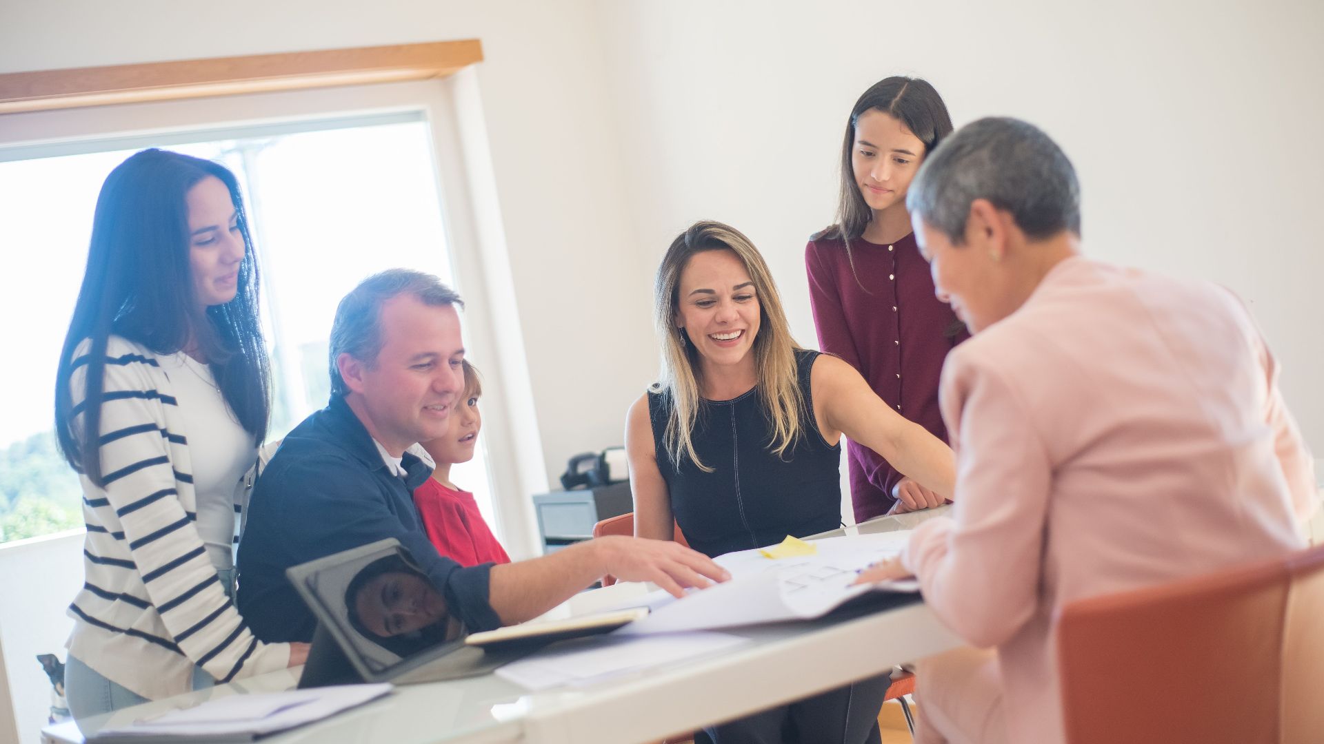 A happy family gathering around a desk during a home meeting, discussing documents.