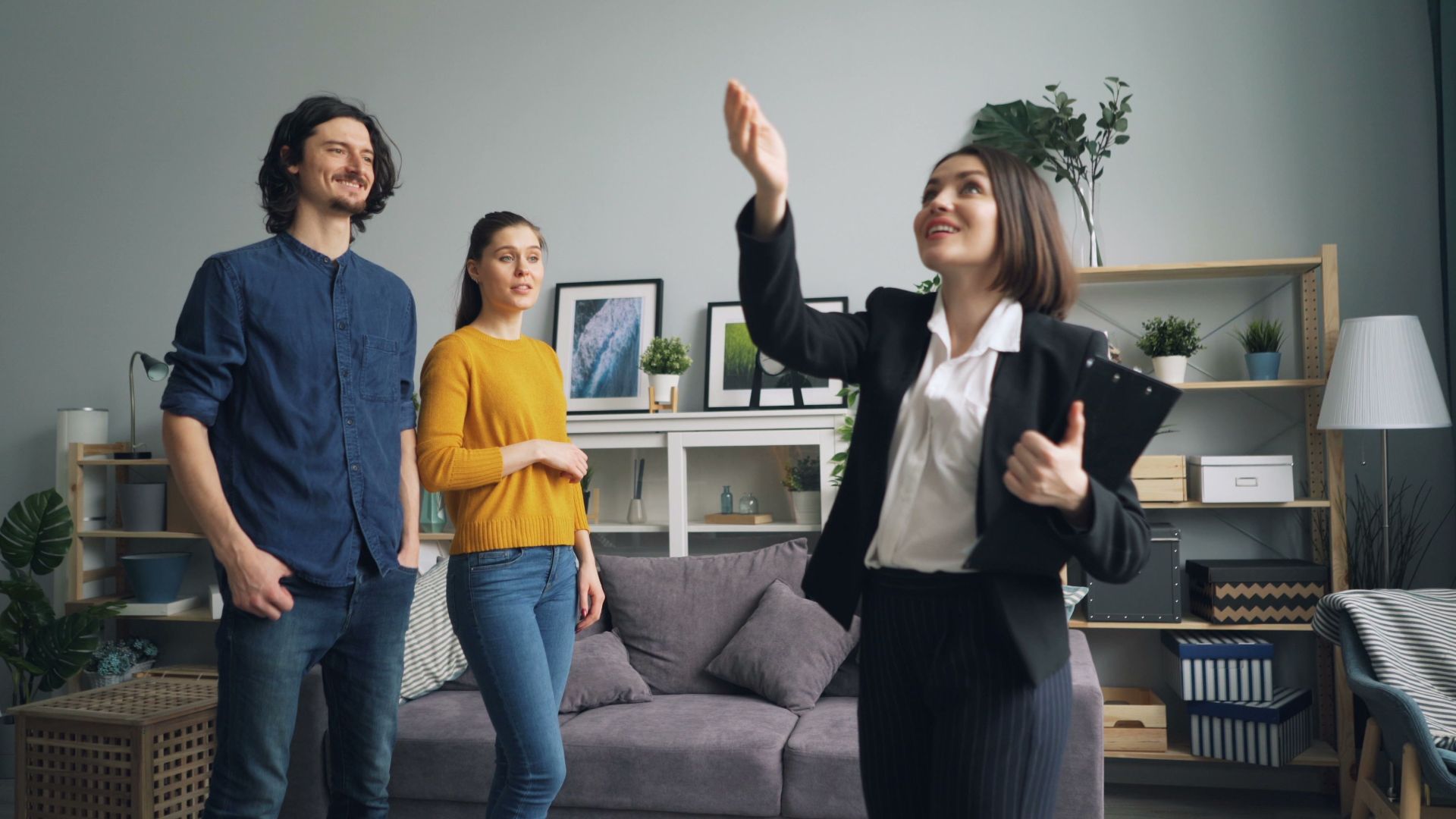 Real estate agent presenting a modern apartment to potential buyers in a stylish living room.
