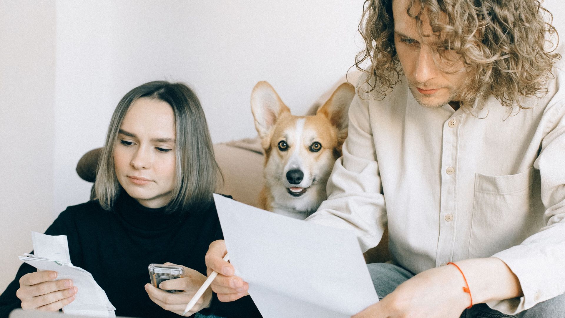 A couple working on a laptop with their dog relaxing nearby, highlighting modern work-life balance.