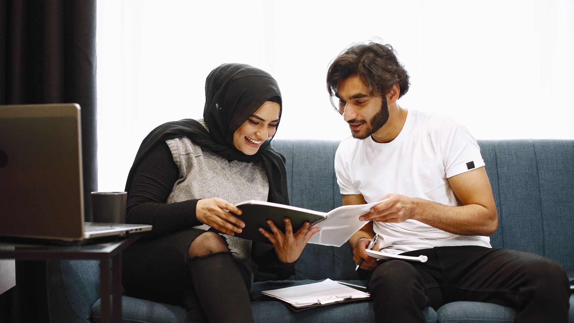 Young couple engaged in reading and studying together on a comfortable sofa indoors.