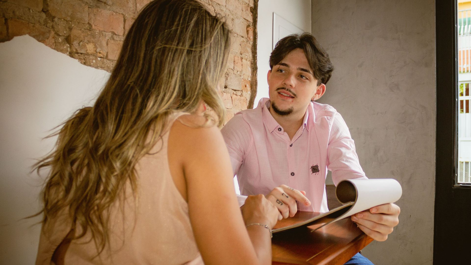 Two adults engaged in a friendly discussion over documents in a cozy café setting.