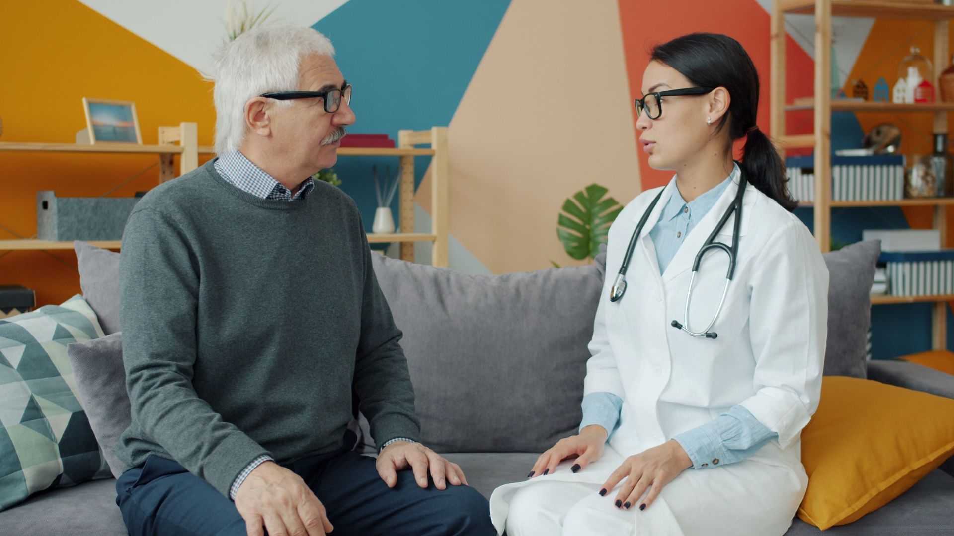Senior man consulting with female doctor in a colorful office setting.