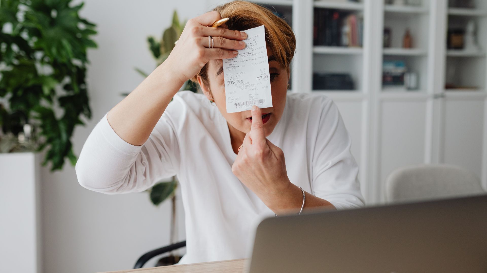 Businesswoman showing a receipt during a home office work session, highlighting technology integration.