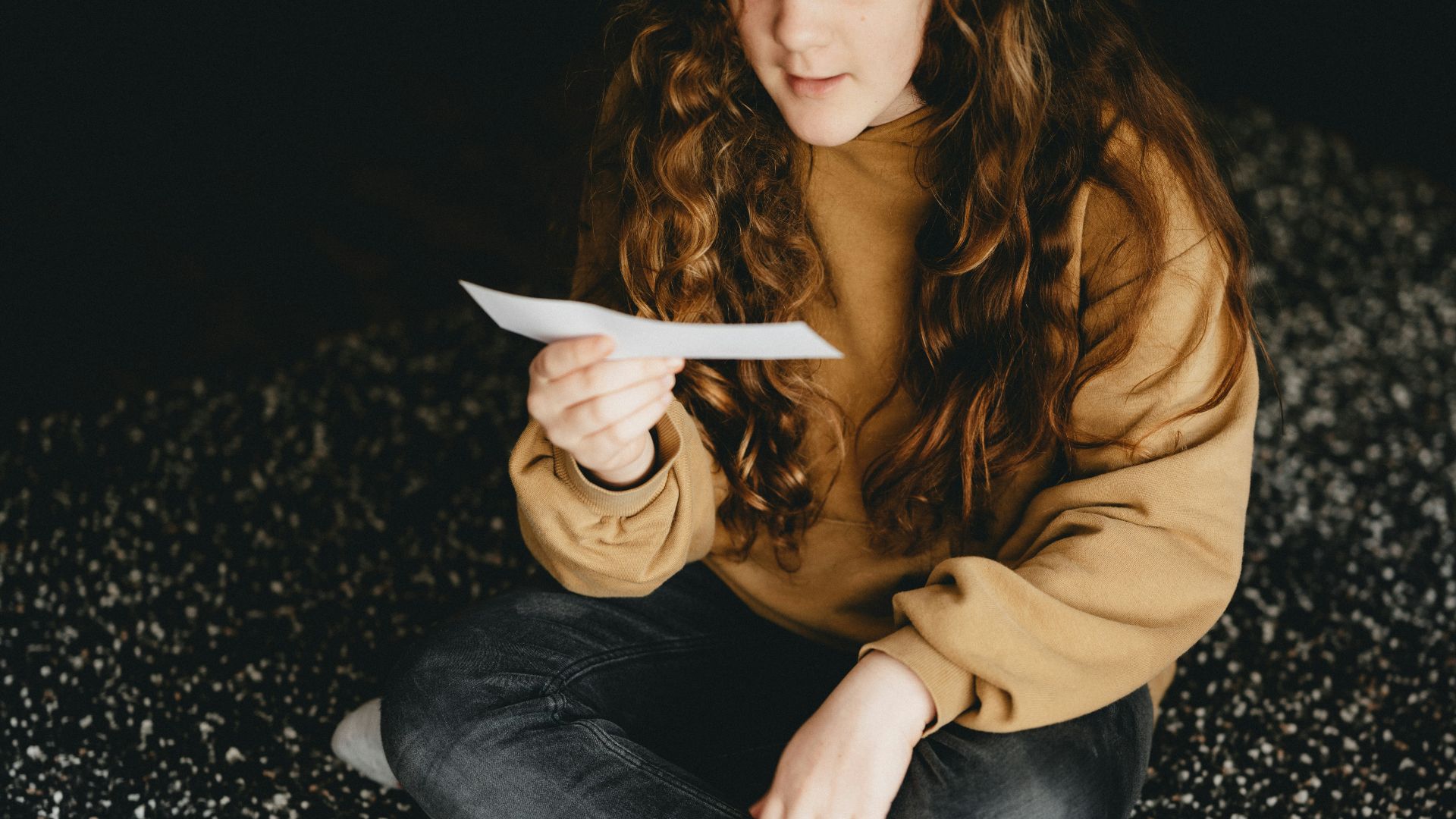woman in brown long sleeve shirt and blue denim jeans sitting on black and white textile