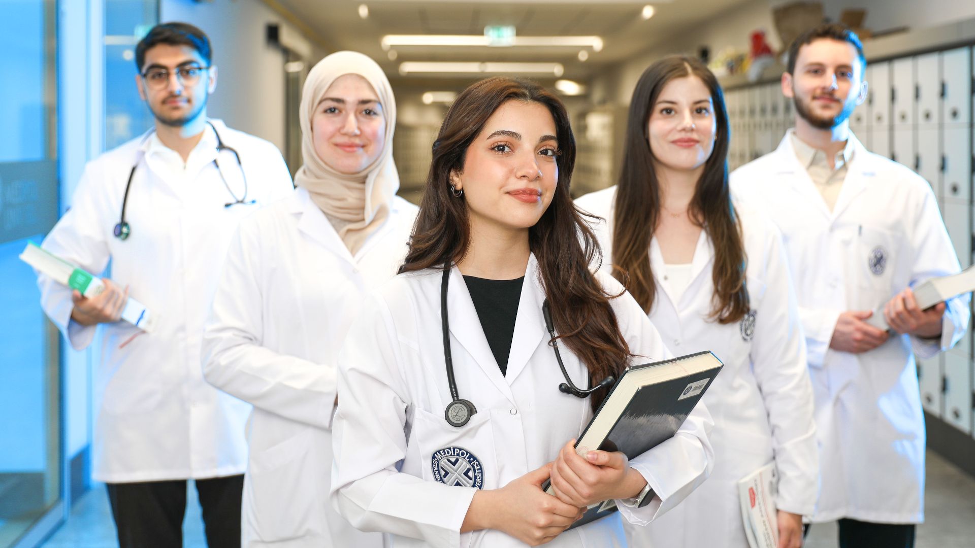 Group of diverse medical students wearing lab coats in university corridor, representing future healthcare professionals.