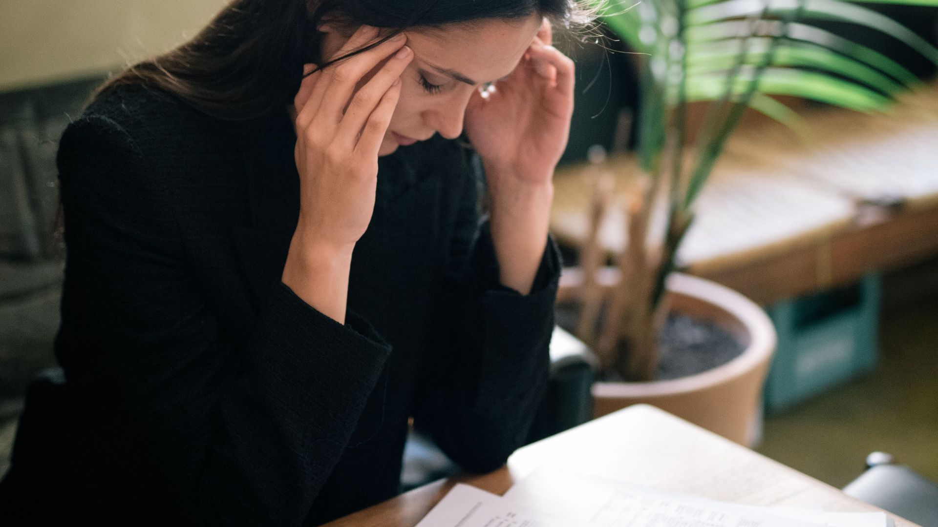 A businesswoman experiencing stress at her desk in a modern office setting.