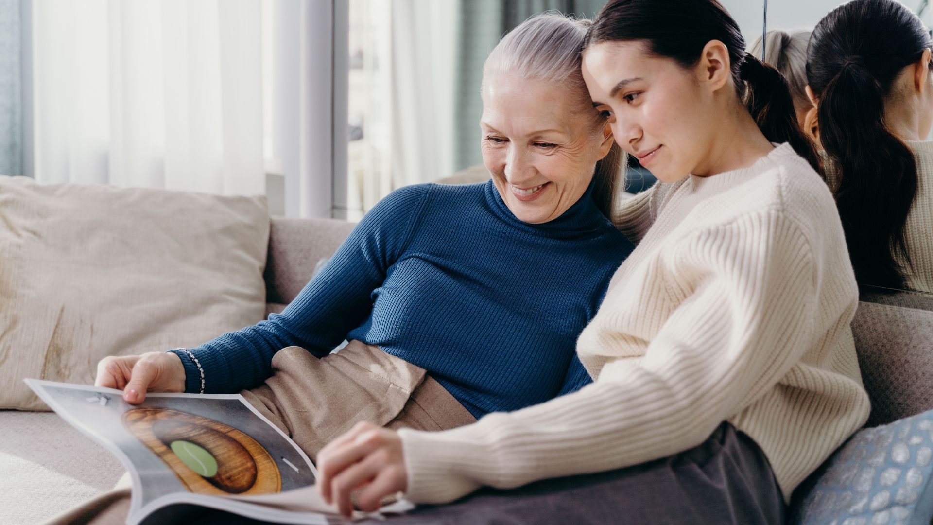 A mother and daughter sharing a joyful moment together on a comfortable couch indoors.