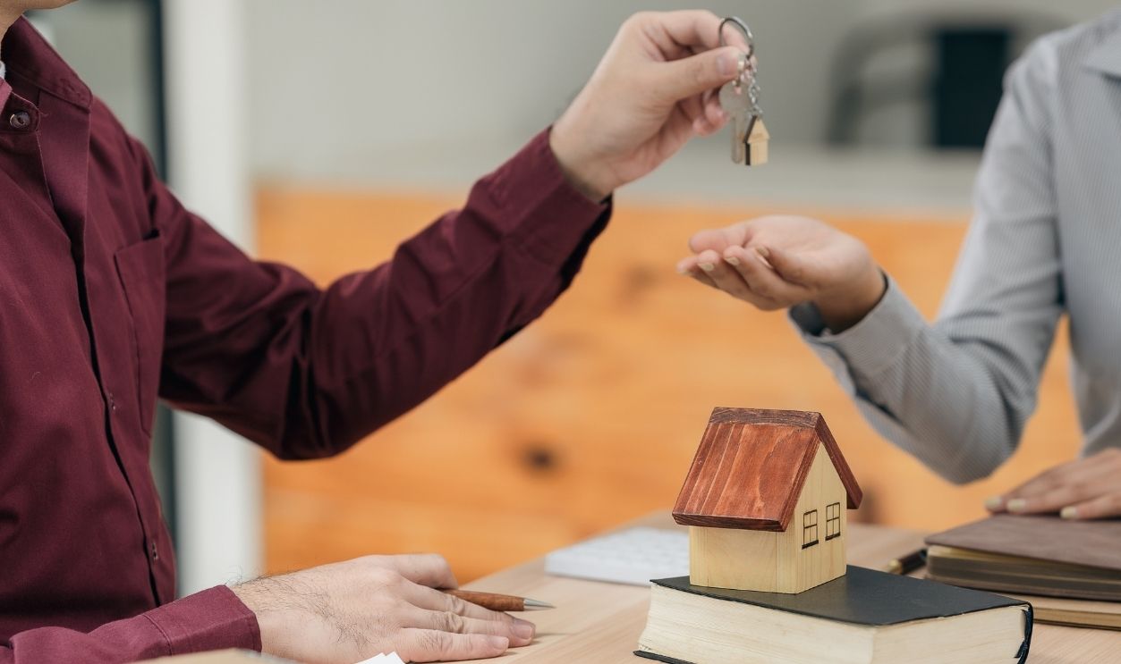 Real estate agents hand over the keys to clients after signing the contract and provide advice to clients on the decision to sign the insurance agreement form.