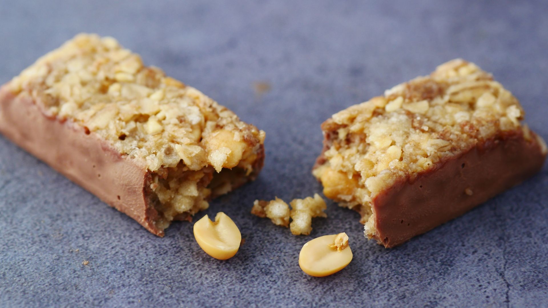 Close-up of a broken chocolate and nut energy bar on a gray surface.