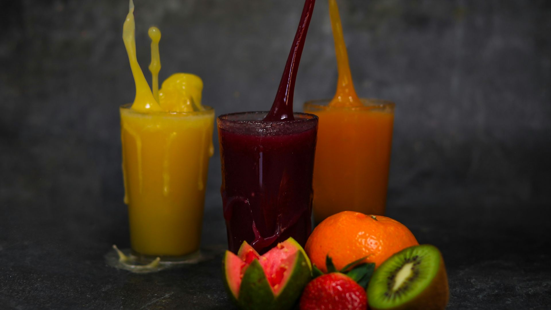 three yellow orange and green juice in clear drinking glasses