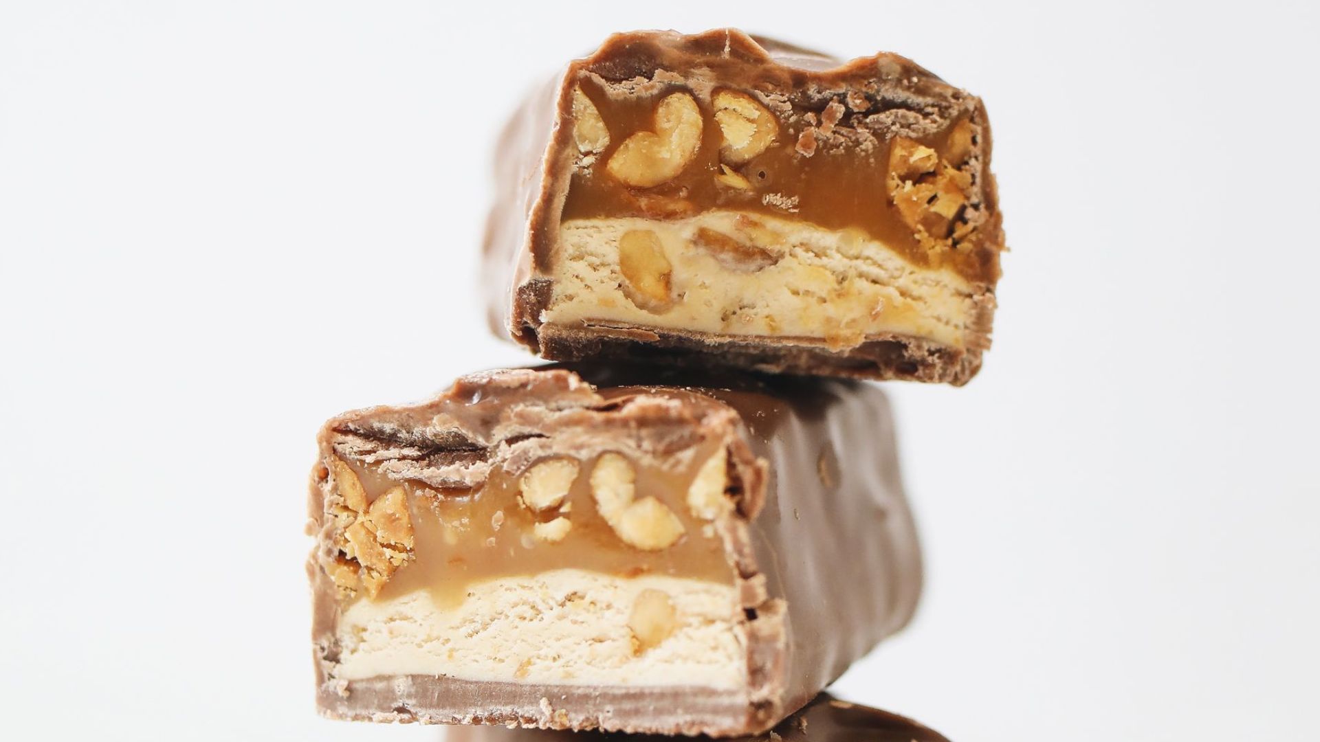 Close-up of stacked chocolate bars with nougat and peanut filling.
