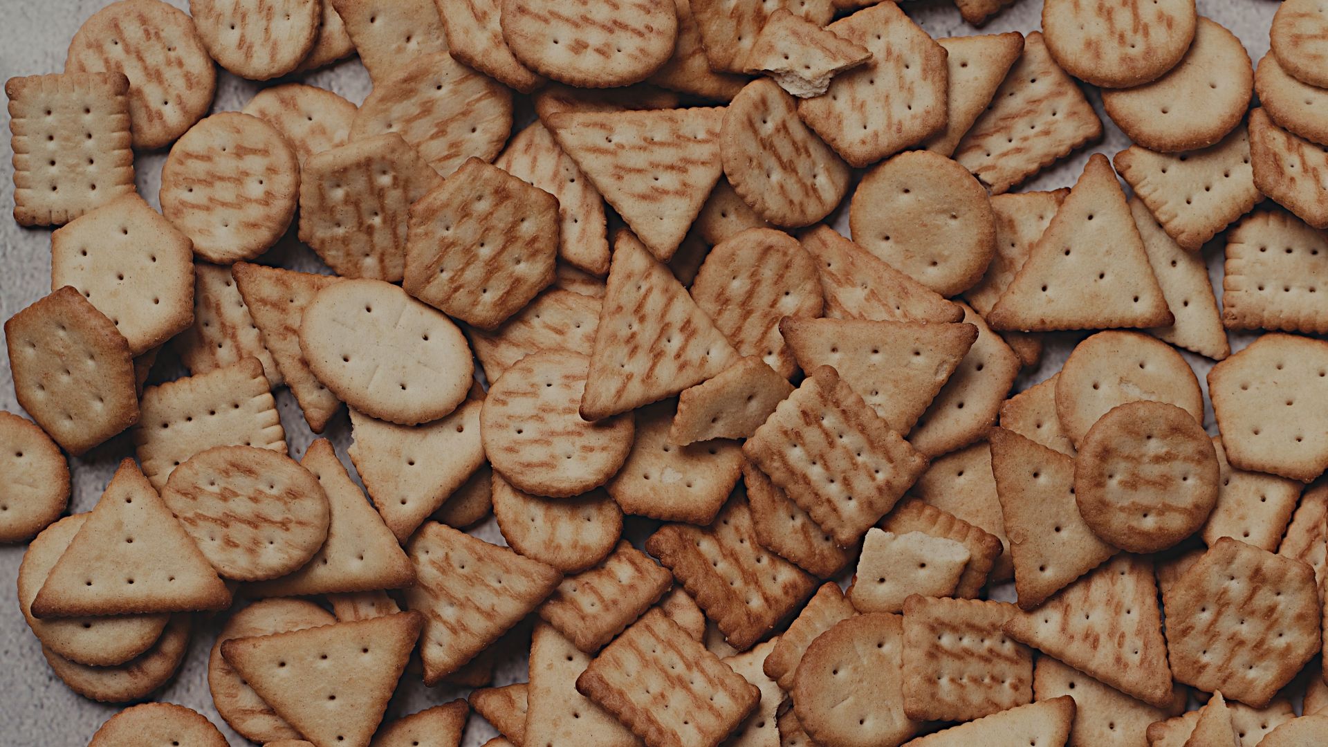 Variety of geometric crackers arranged on a textured surface.