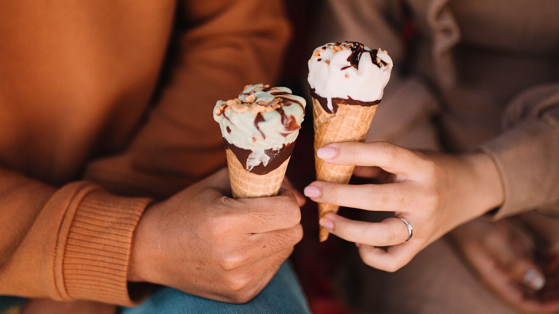 Close-up of two people holding ice cream cones, enjoying a sweet treat together.
